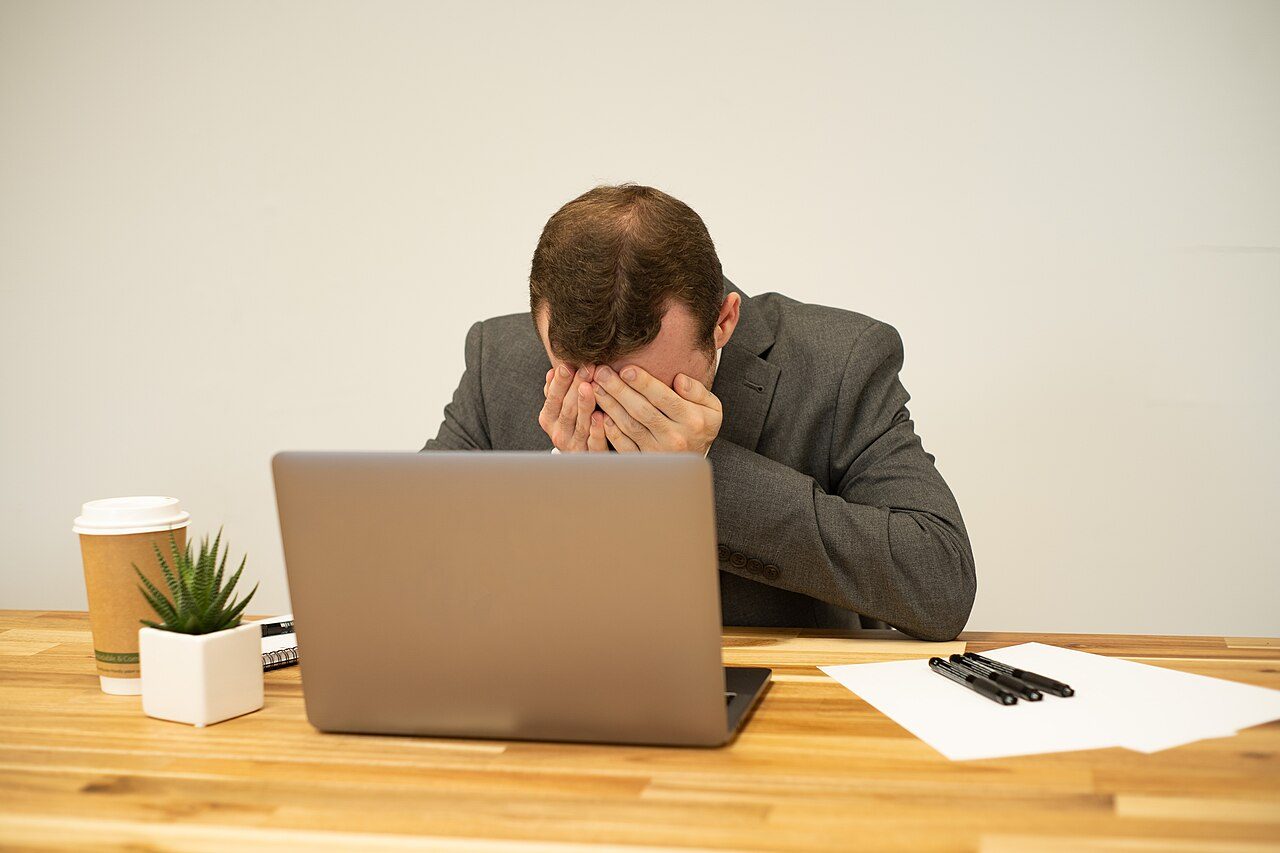 A man at a laptop with his head in his hands